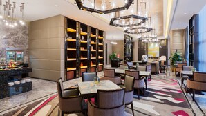 A modern hotel lobby with a marble reception desk, multiple seating areas, and a large bookshelf. - Wanda Realm Maanshan (Ma'anshan)