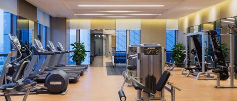 A modern gym with treadmills, weight machines, and dumbbells.