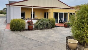 A yellow building with a red roof, a covered porch, and several potted plants. - Austral Place 88 via Merri River (Dennington)