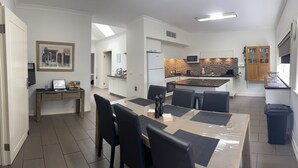 A modern kitchen with a microwave, stove, and cabinets. There is a dining area with a table and chairs. - Austral Place 88 via Merri River (Dennington)