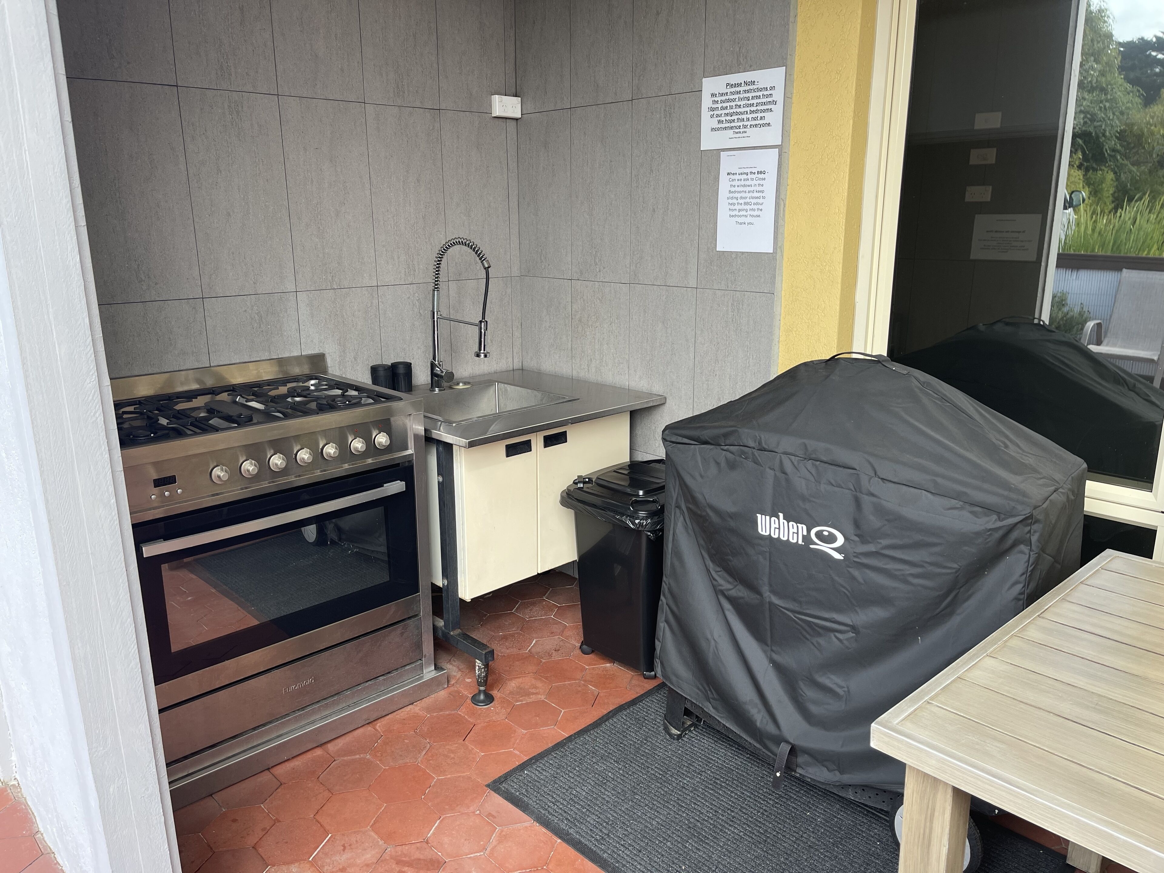 Una cucina compatta con piano cottura a gas, forno, lavello e copertura per barbecue Weber.
