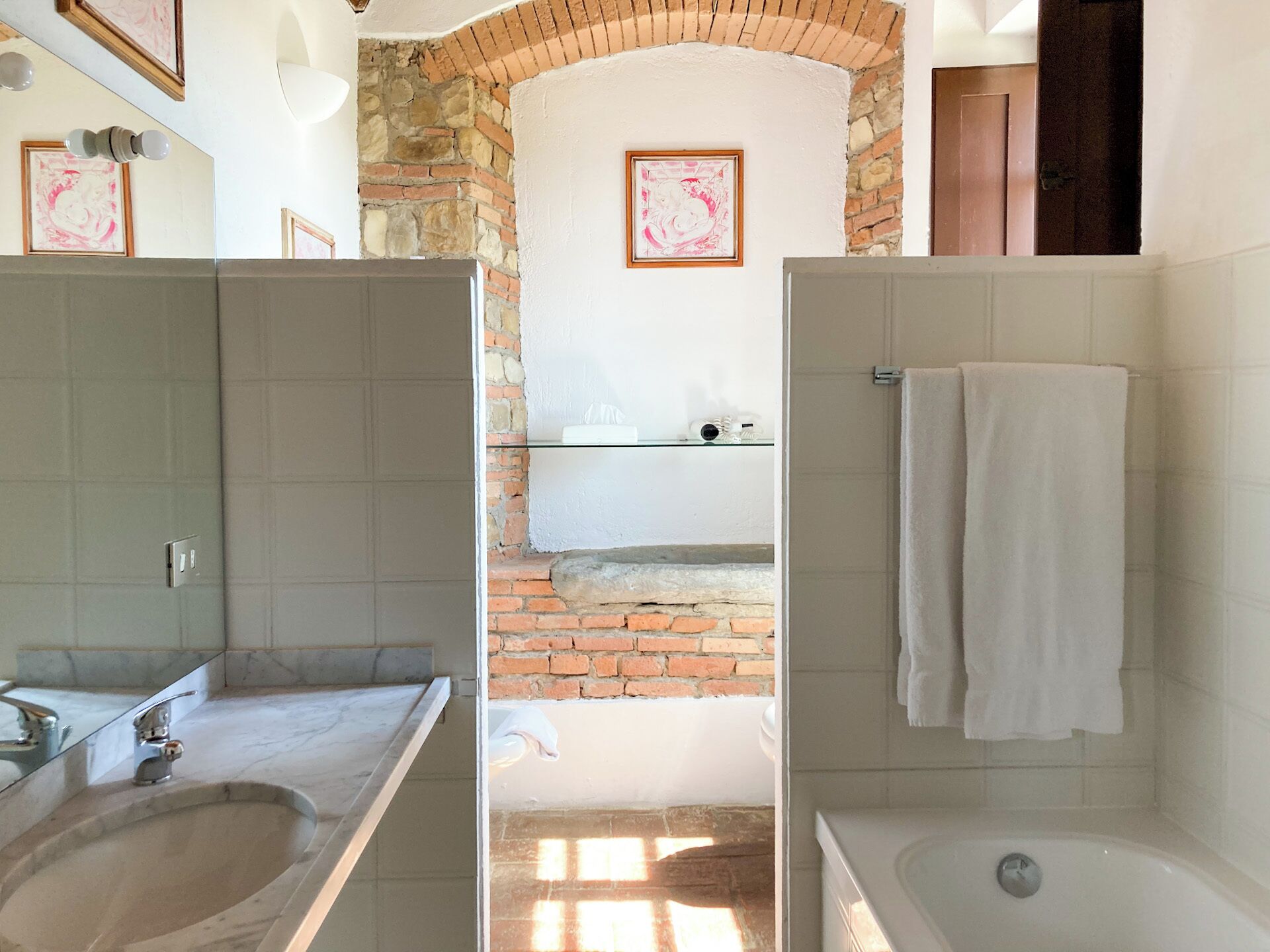 Un bagno con lavabo in marmo, vasca e parete in pietra.