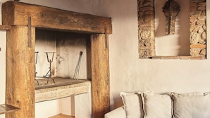 A rustic room with exposed wooden beams, a stone fireplace, and a white sofa.