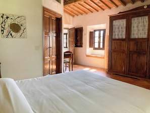 Un dormitorio con cama, armario de madera y una silla.