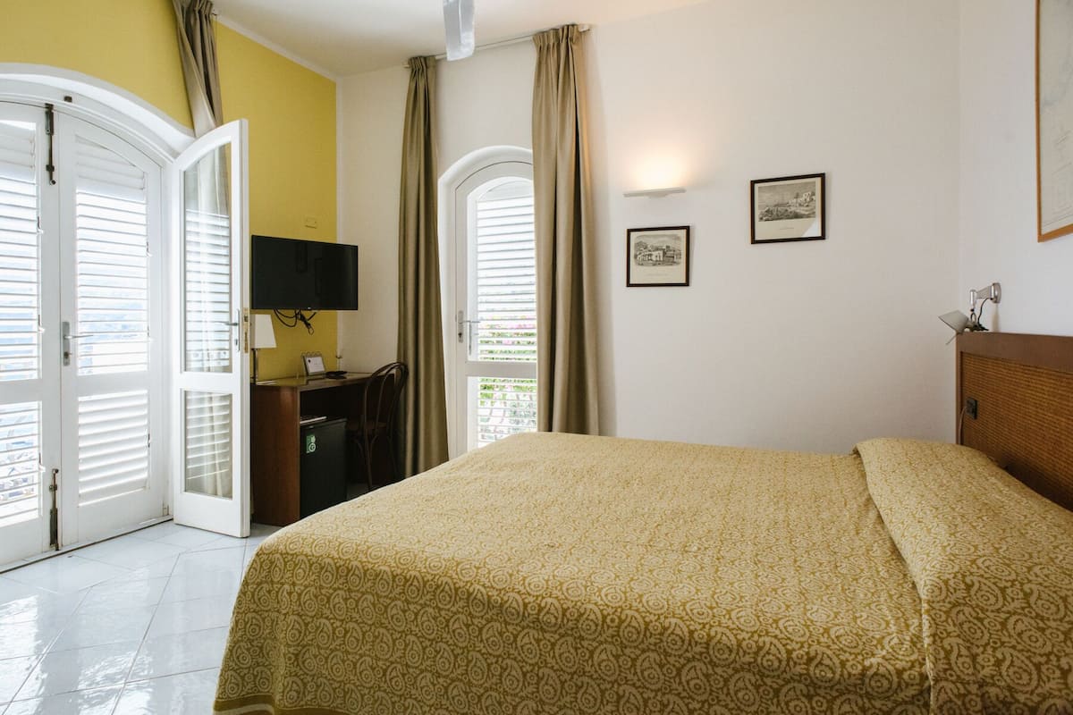 Une chambre d’hôtel avec un lit, un bureau, une télévision et deux tableaux encadrés au mur.