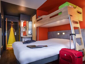 A hotel room with a bunk bed, a desk with a mirror, a suitcase, and a laptop on the bed. - ibis budget Amboise (Amboise)
