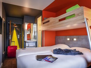 A hotel room with a bunk bed, a single bed, a bathroom with a sink, and a suitcase. - ibis budget Amboise (Amboise)