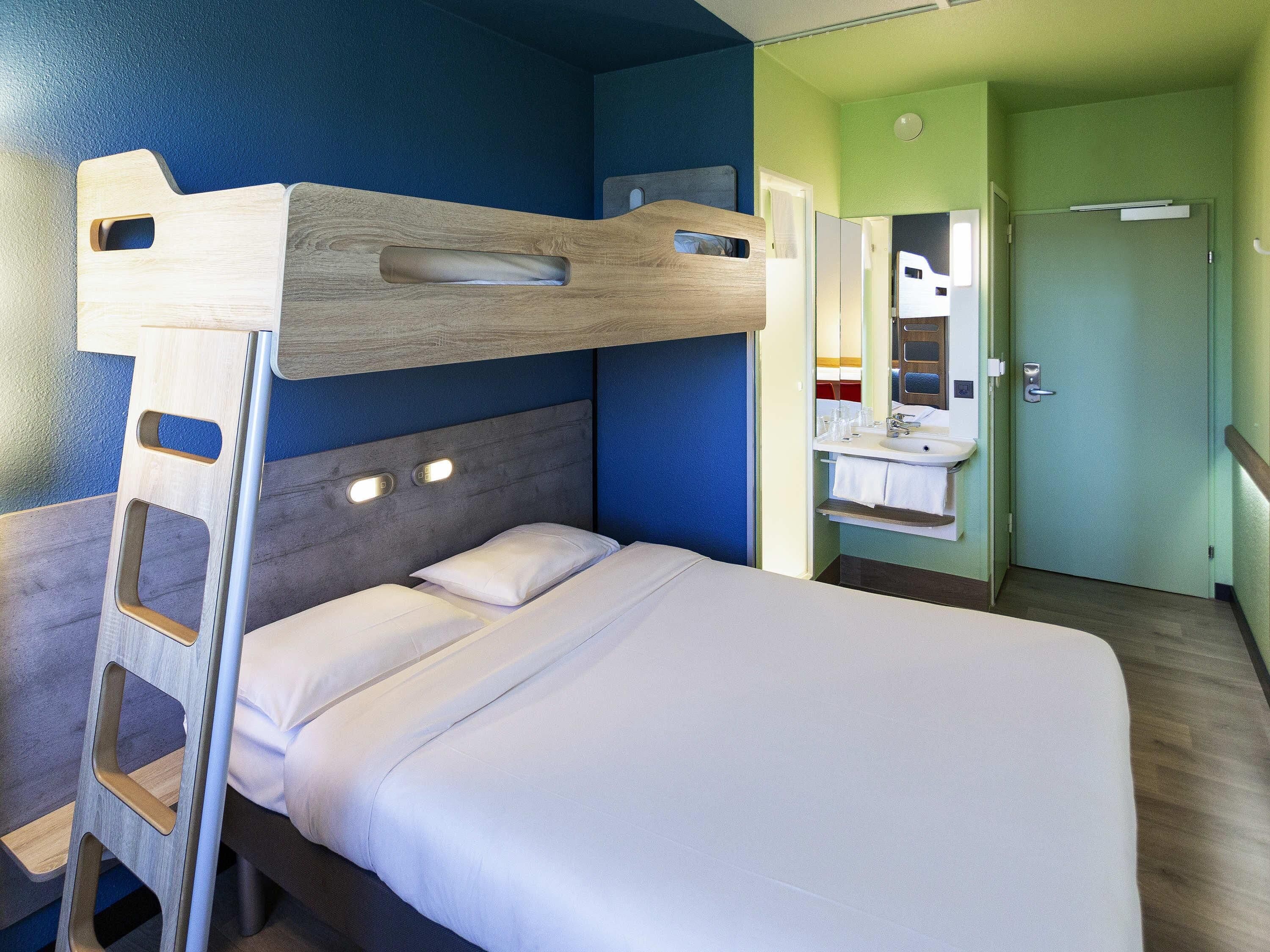 Een stapelbed met een ladder, een nachtkastje en een spiegel.