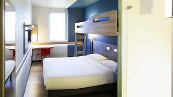 Una habitación de hotel pequeña con una cama litera, un escritorio y una silla, además de un ventanal.