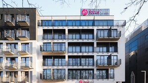 A multi-story hotel with balconies, a clear sky, and a parking sign. - Hotel Focus Poznań (Poznan)