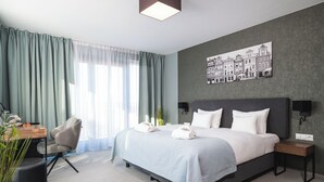 A modern hotel room with a large bed, a desk, a chair, and a wall-mounted TV. - Hotel Focus Poznań (Poznan)