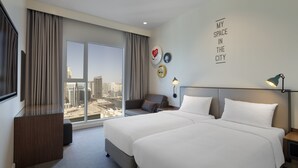 Ein Hotelzimmer mit zwei Betten, einem Schlafsofa, einem Fernseher und einem großen Fenster mit Blick auf die Stadt.