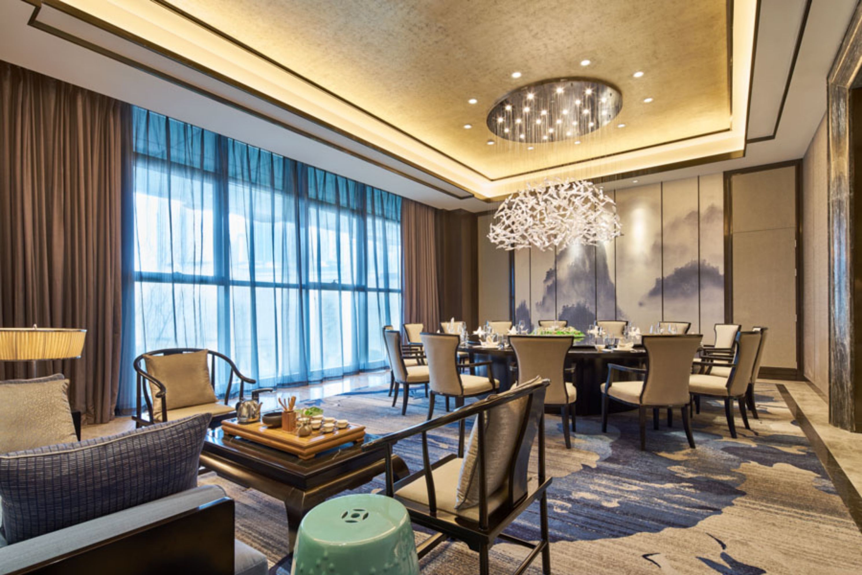 A spacious hotel room with a large dining area, a sofa, and a chandelier.