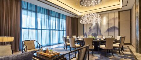 A spacious hotel room with a large dining area, a sofa, and a chandelier.