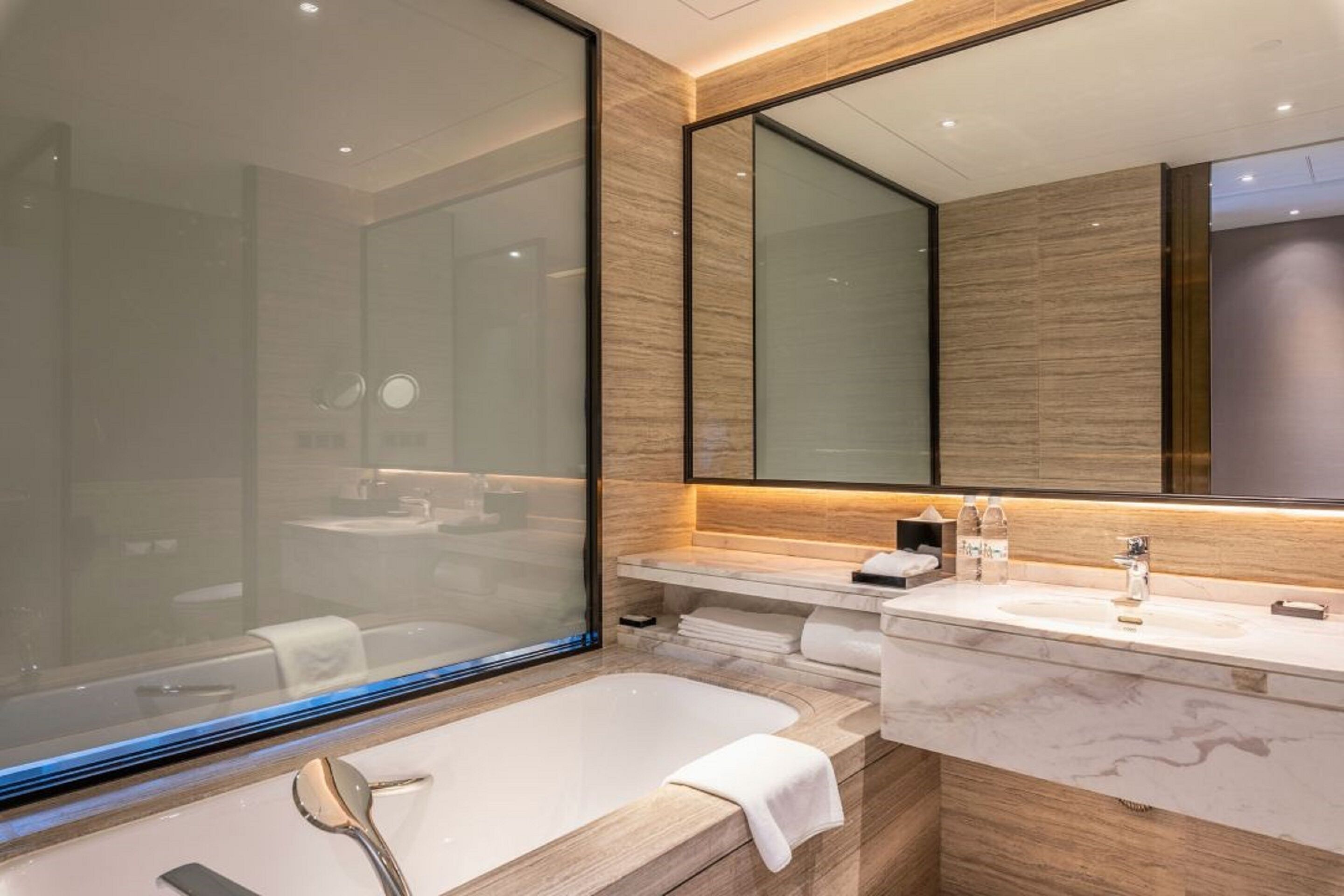 Un baño moderno con una bañera grande, un tocador con espejo y una cabina de ducha de vidrio.