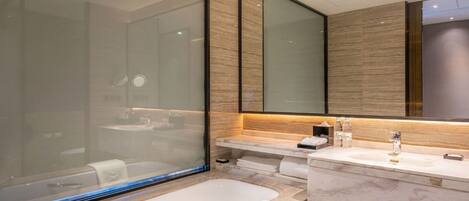 Un baño moderno con una bañera grande, un tocador con espejo y una cabina de ducha de vidrio.