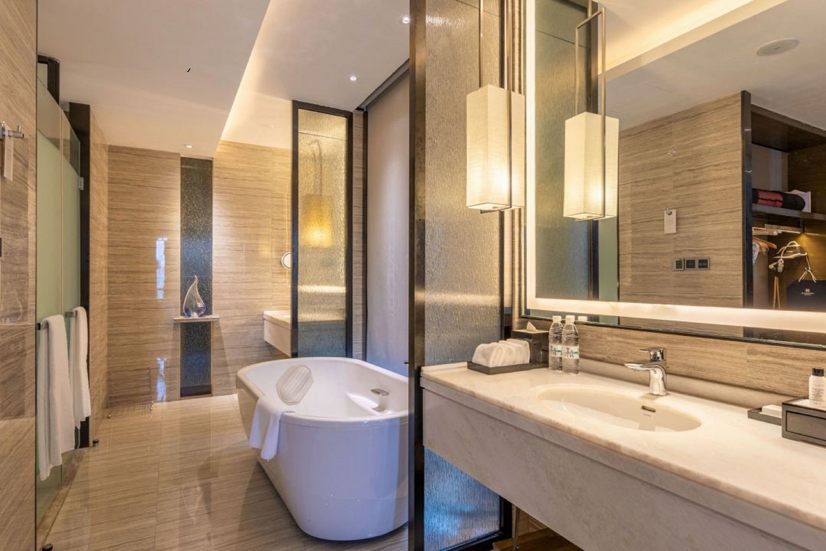 A modern bathroom with a freestanding bathtub, a large mirror, and a vanity with a sink and towel rack.