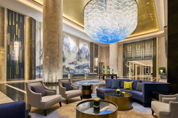 Un hall d’entrée spacieux, doté d’un mobilier moderne, d’un grand lustre et d’une fresque murale.