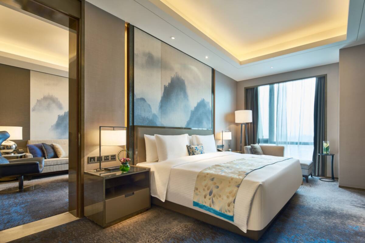 Ein modernes Hotelzimmer mit einem großen Bett, einem Schreibtisch, einem Stuhl und einem Sofa.