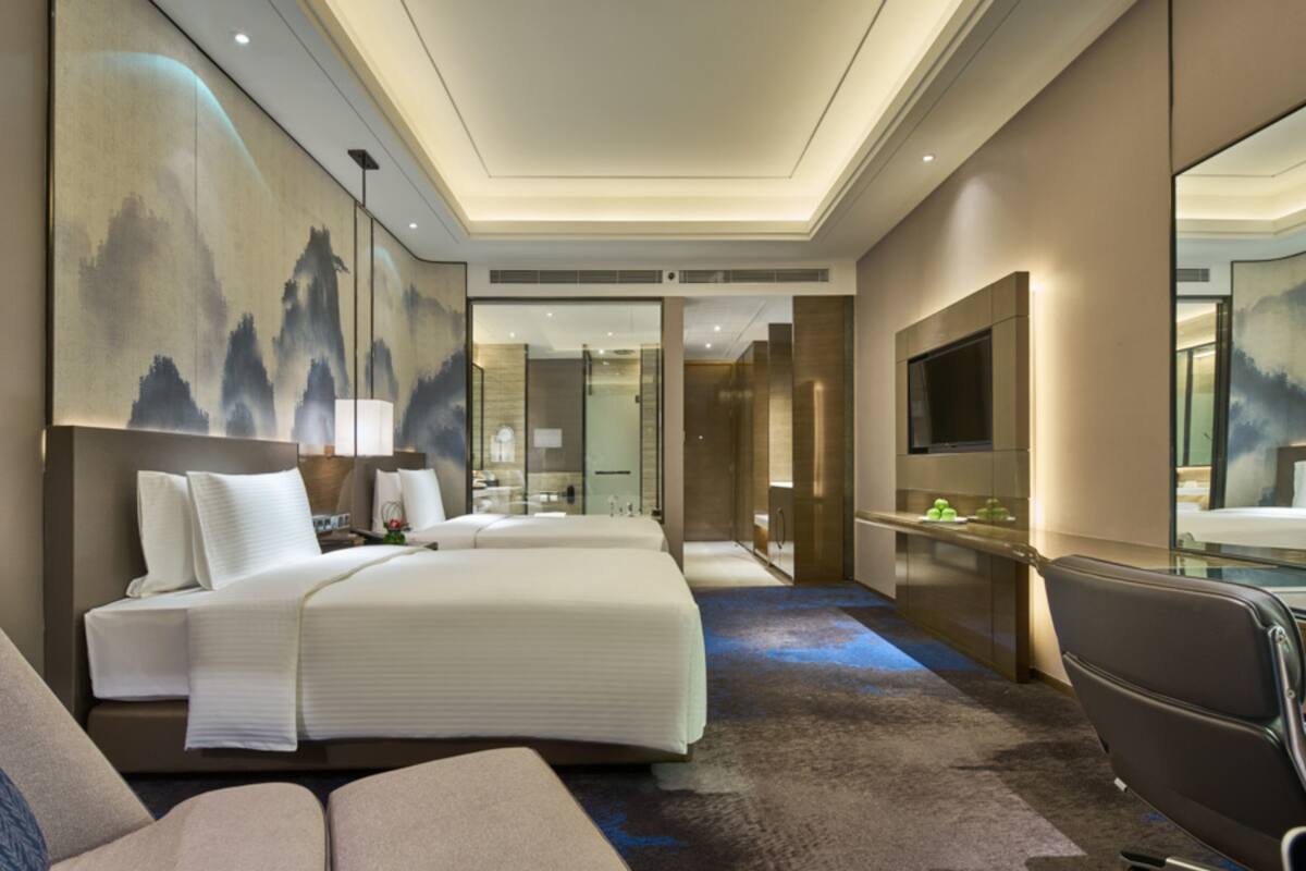 Ein modernes Hotelzimmer mit einem großen Bett, einem Schreibtisch, einem Sessel und einem Fernseher.