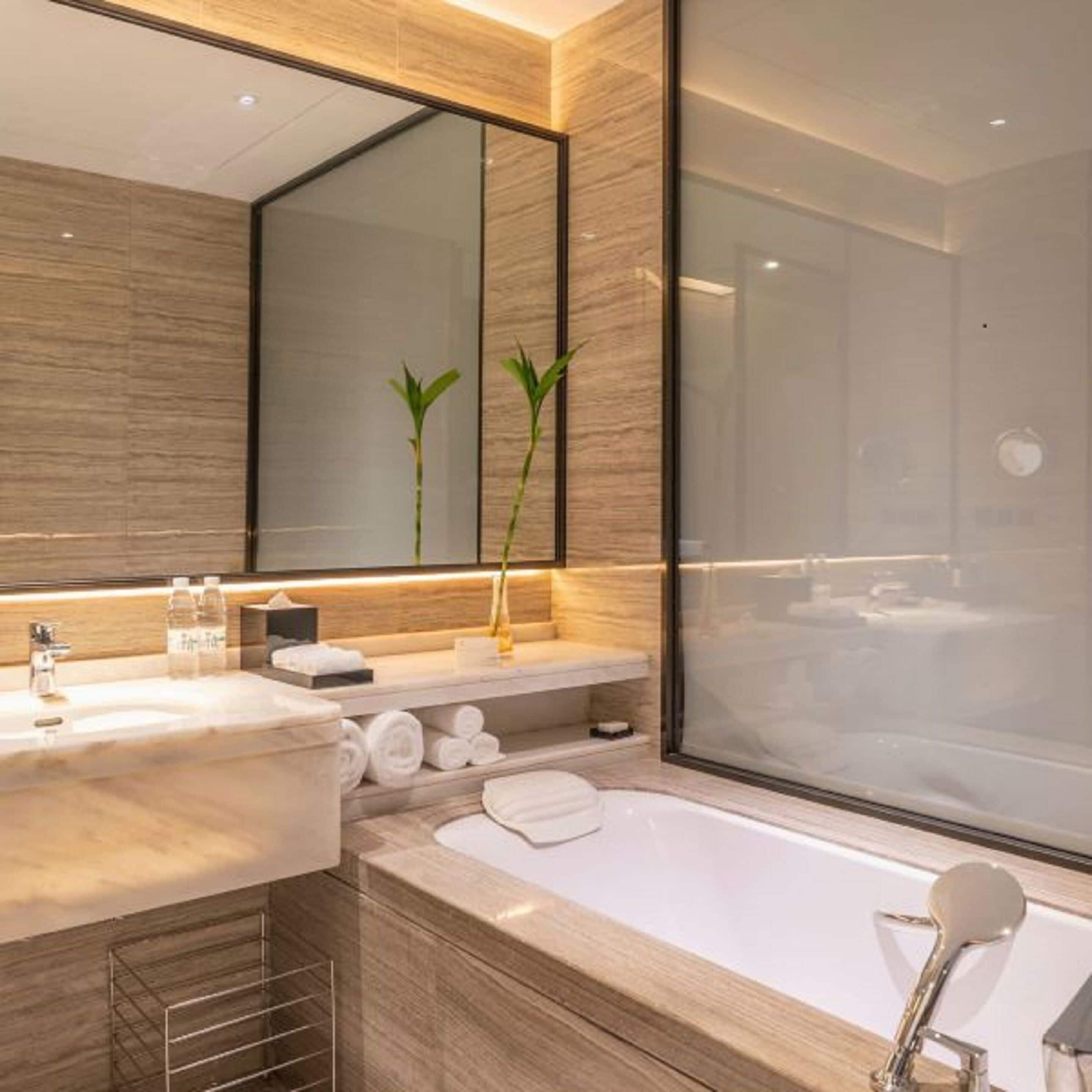 Un baño moderno con un espejo grande, dos plantas, una bañera y una ducha.