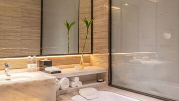 Un baño moderno con un espejo grande, dos plantas, una bañera y una ducha.