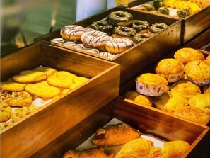 Une variété de produits de boulangerie, notamment des beignets, des muffins et des pâtisseries, présentés dans des boîtes en bois.