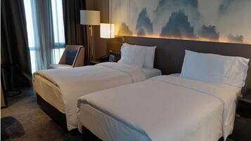 A hotel room with two beds, a large painting on the wall, and a nightstand with a lamp.