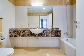 Een badkamer met een witte wastafel, een bad en een douche.