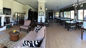 Ein geräumiges Wohnzimmer mit einer Couch, Sesseln und einem Essbereich mit mehreren Tischen und Stühlen.