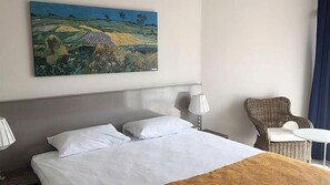 A hotel room with a large bed, two bedside lamps, a wicker chair, and a table. - KerpeDiem Otel (Kandira)