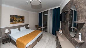 Ein modernes Hotelzimmer mit einem großen Bett, einem Bild an der Wand, einem kleinen Tisch und einem Spiegel.