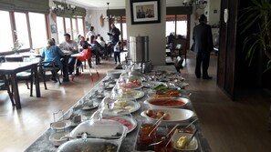 A buffet setup with various food items and a dining area with tables and chairs. - KerpeDiem Otel (Kandira)