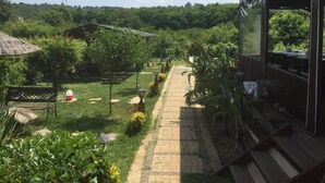 Eine Terrasse mit Pflasterweg, Sitzgelegenheit und Blick auf einen bewaldeten Hügel.