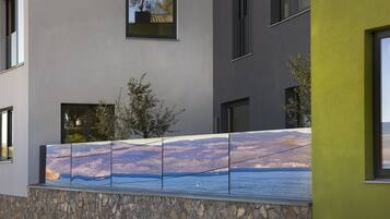 A modern building with a stone base, large windows, and a mural of a coastal landscape.