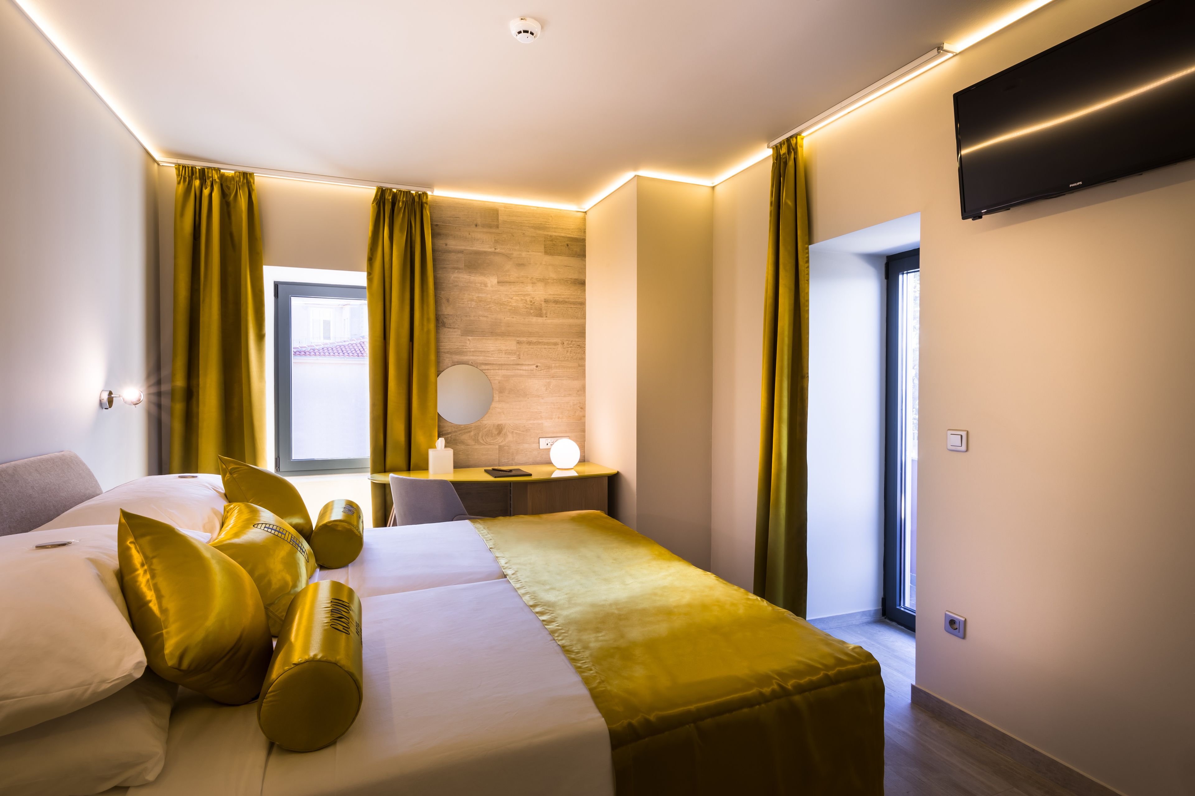 A modern hotel room with a bed, bedside table, lamp, and a view of the outside.