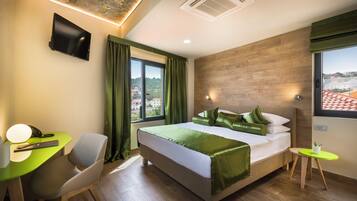 A modern hotel room with a bed, desk, chair, and a view of the city.