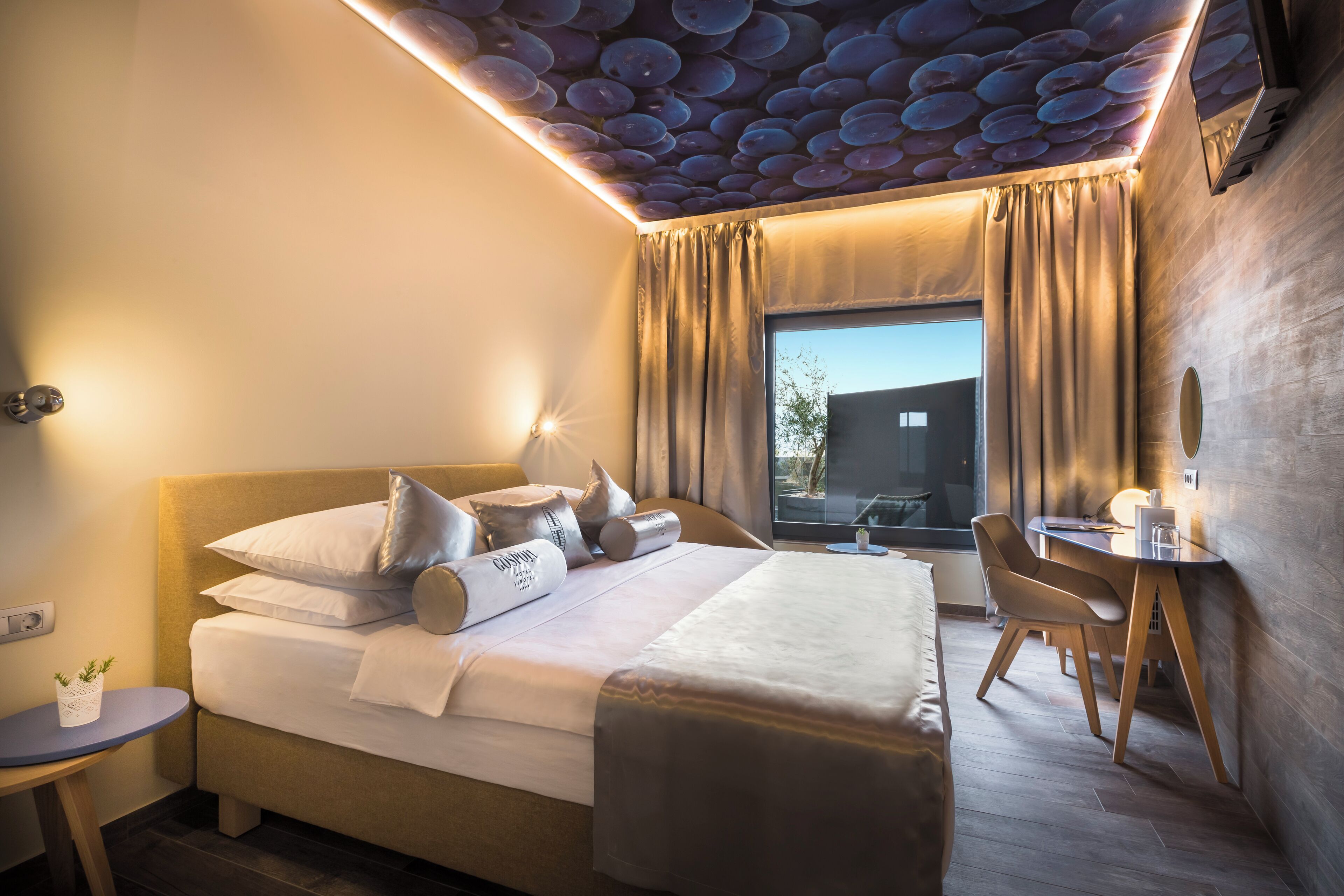Una habitación de hotel con una cama, un escritorio y una ventana.