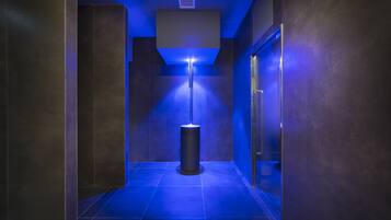 A hallway with a blue-lit floor, a cylindrical light fixture, and a door on the right.