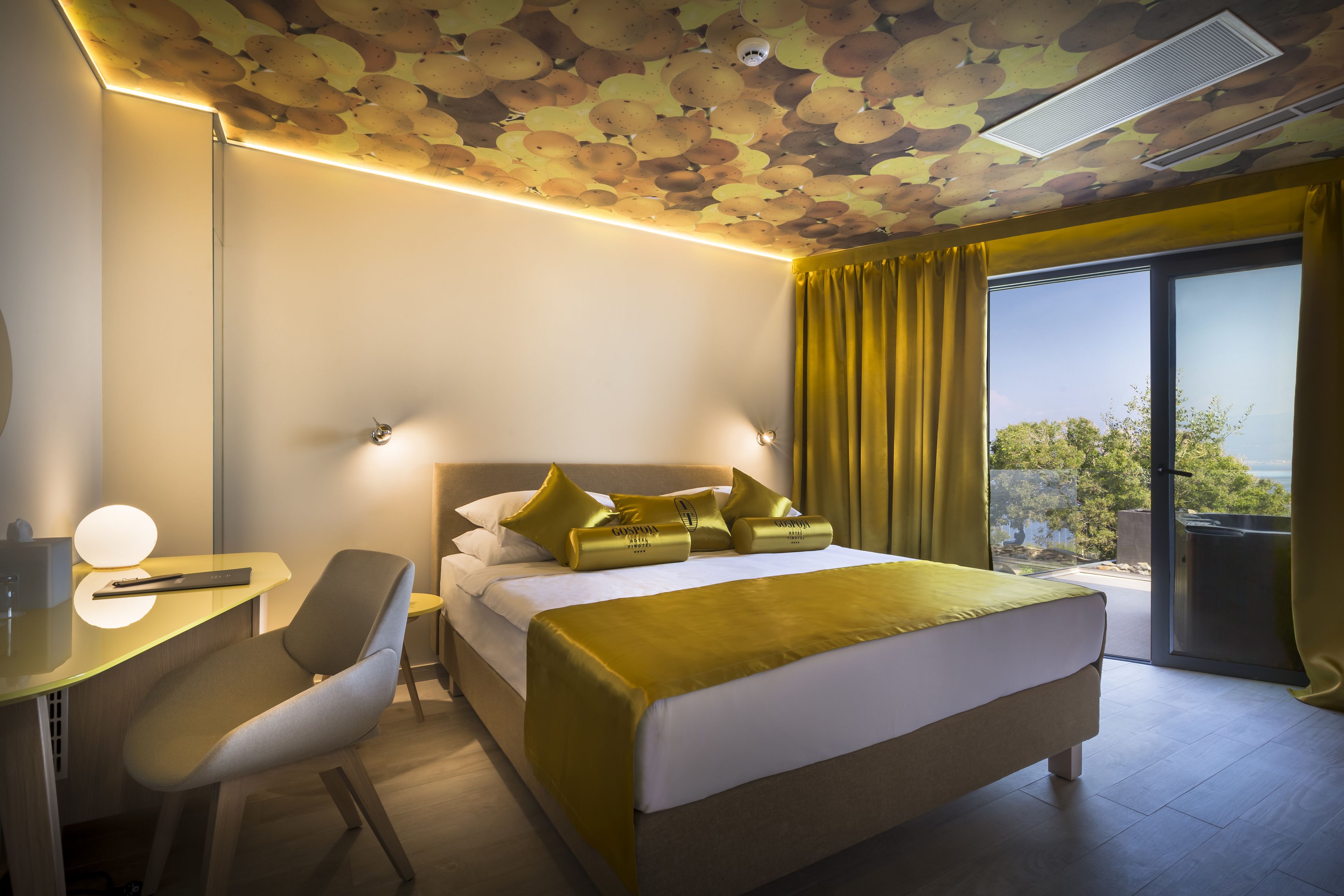A modern hotel room with a bed, desk, and chair.