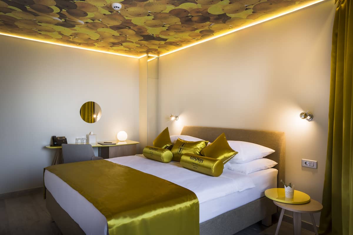 Una habitación de hotel con cama, mesita de noche, lámpara y escritorio con silla.