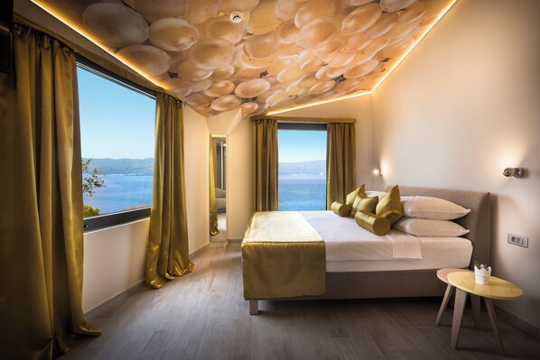 Un dormitorio con una cama grande, dos ventanas con cortinas, un techo con un diseño único y una pequeña mesa redonda.