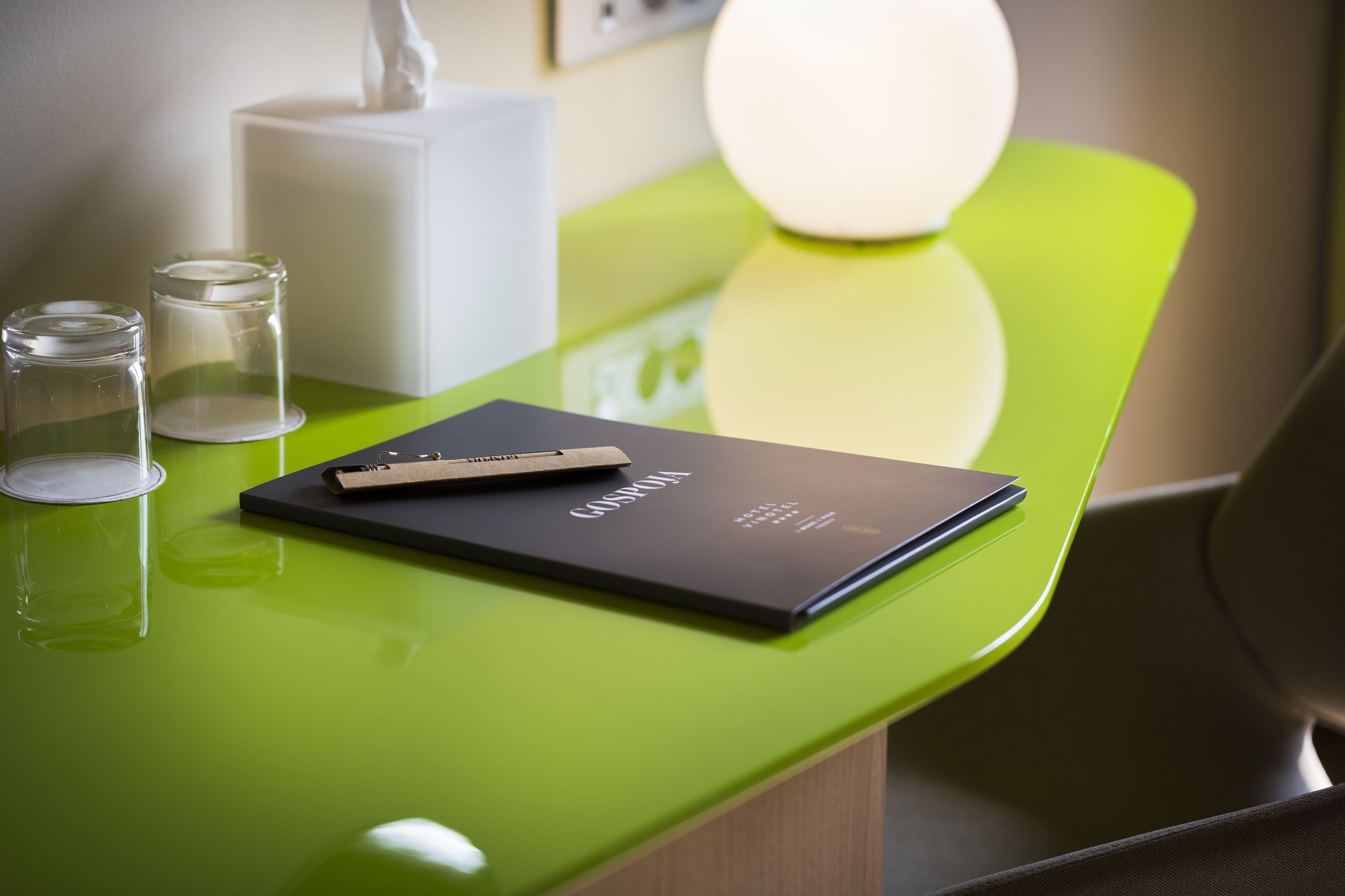 Un bureau vert avec un dossier noir portant l’inscription « CASPONA » et deux verres transparents.