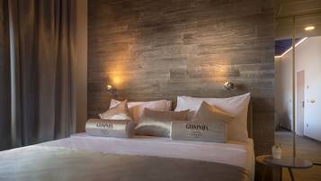 Habitación de hotel con pared de madera, una cama con ropa de cama blanca y dos luces fijadas a la pared.