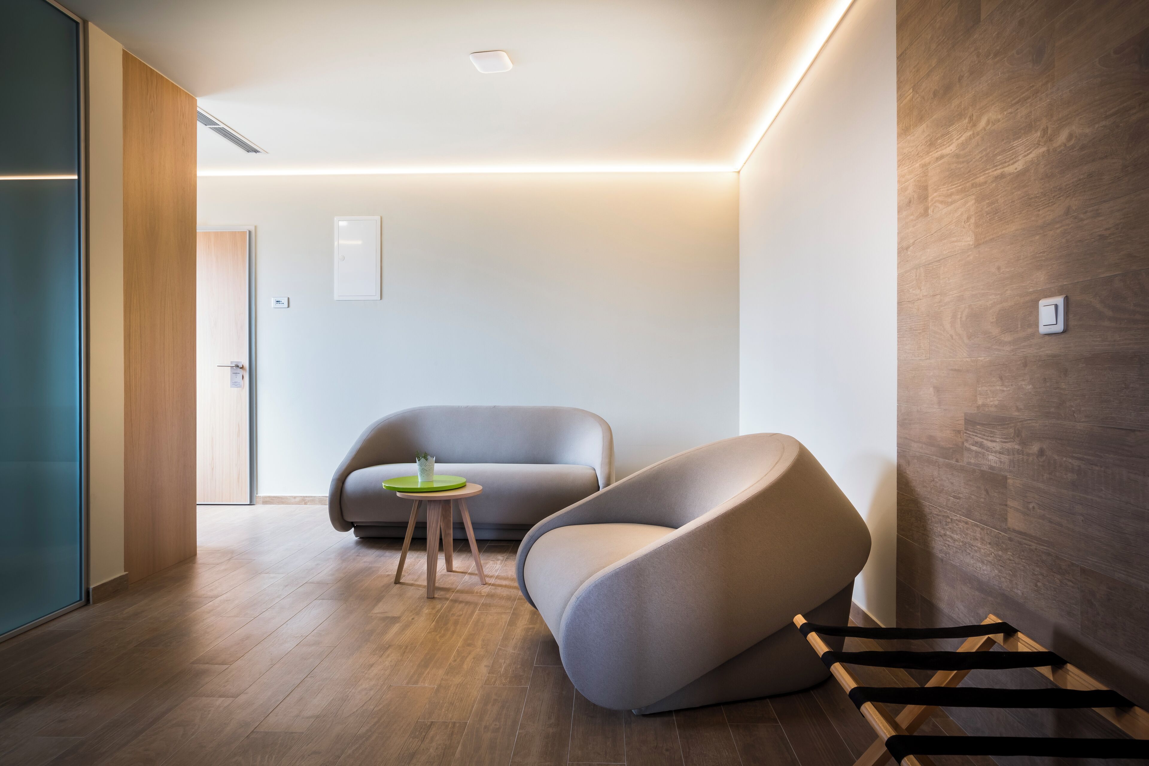 Ein modernes Interieur mit einer gebogenen Couch, einem kleinen runden Tisch und Holzboden.