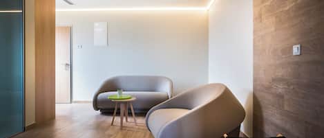 Un interior moderno con un sofá curvo, una mesita redonda y suelo de madera.