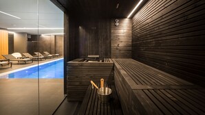 Una sauna amb seients de fusta, una petita piscina i un cubet amb una escova.