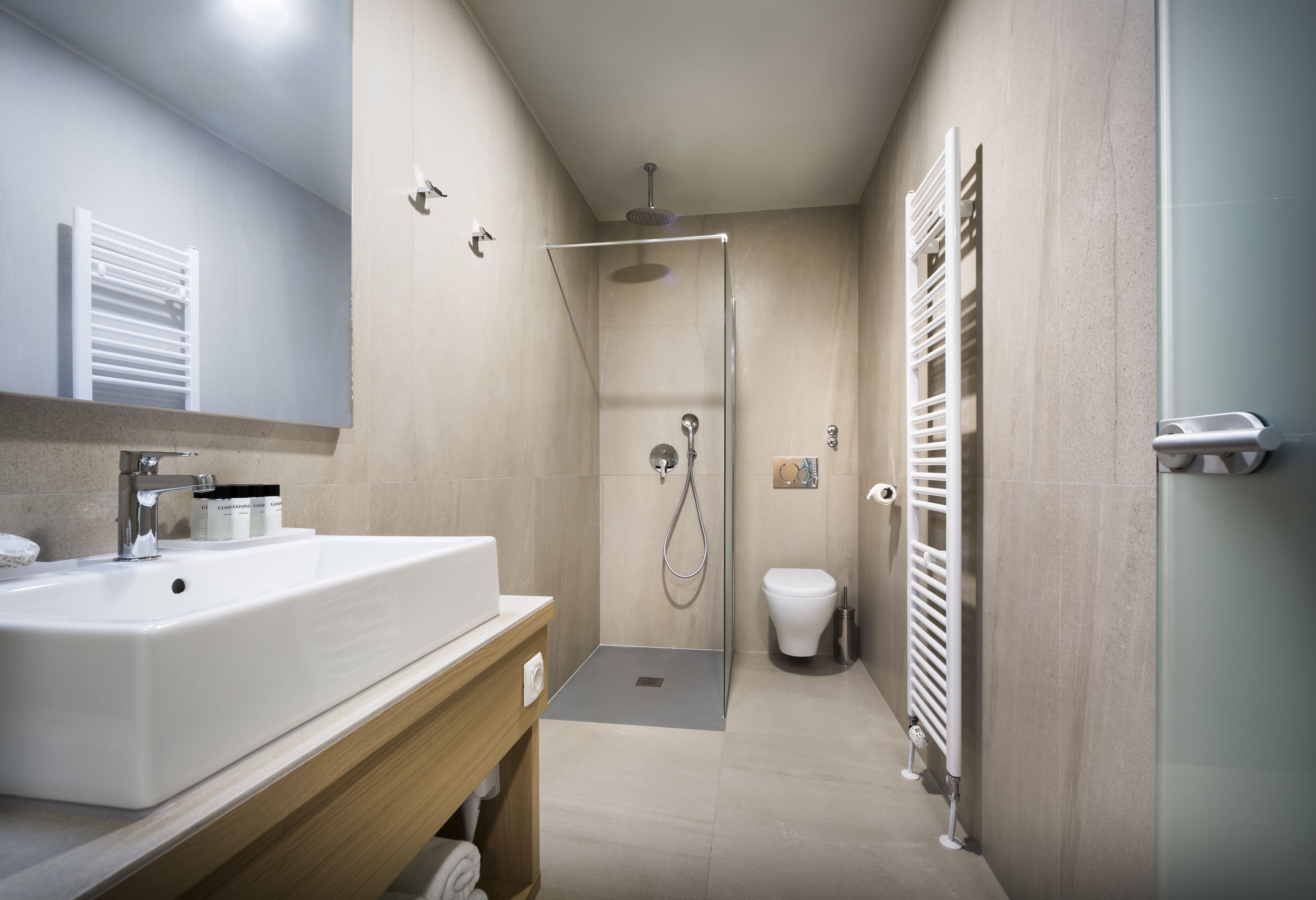 A modern bathroom with a large sink, a shower, and a toilet.