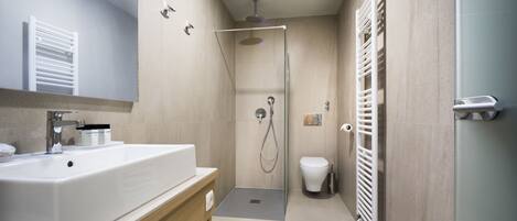 A modern bathroom with a large sink, a shower, and a toilet.