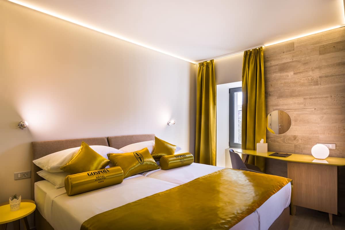 Una habitación de hotel con cama, mesita de noche y escritorio con lámpara.
